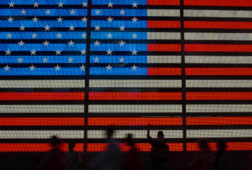 An Occupy Wall Street movement activist raises his fist while protesting in front of a digital flag of the United States in Manhattan's Time Square in New York on July 17, 2012.  REUTERS/Adrees Latif  (UNITED STATES - Tags: CIVIL UNREST SOCIETY) - GM1E87I0W6M01