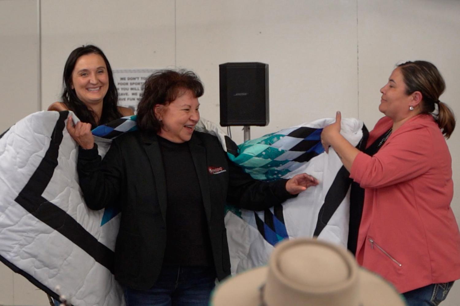 Lakota Vogel, Four Bands Community Fund and Kerry Shabi, Montana Native Growth Fund present Angie Main, Executive Director of NACDC Financial Services, a star quilt in honor of her work in planning the Mountain | Plains Indigenous Finance Gathering at Blackfeet Nation, Montana.