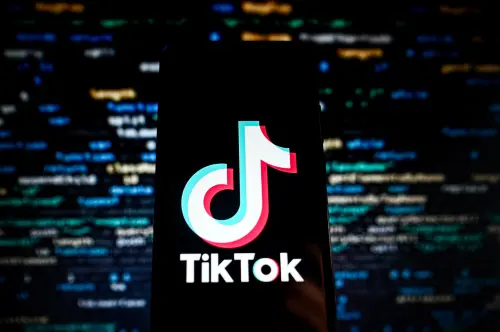 In this photo illustration a TikTok logo is displayed on a smartphone with programing codes on the background.