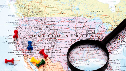 A map of the United States with pins and magnifying glass to signify which states and localities are receiving the greatest number of immigrants