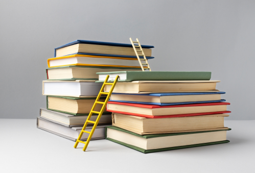 Stacks of books with ladders representing primary, secondary, and higher education in the U.S.