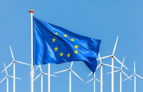 Official flag of the European Union in front of a large wind park with wind turbines