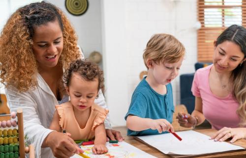 Childcare workers helping toddlers with art projects