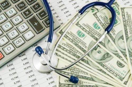 U.S. dollars, stethoscope, and calculator representing health care costs