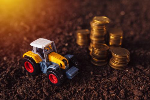 Toy tractor and stack of coins on a patch of dirt
