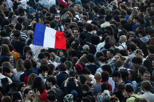 A demonstrator holds a French flag as people gather at the Place de la Republique after partial results in the second round of the early French parliamentary elections, in Paris, France, July 7, 2024.