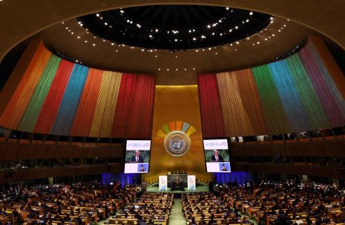 Wide view of the inside of the United Nations General Assembly Building, with the walls lit up in the colors of the Sustainable Development Goals