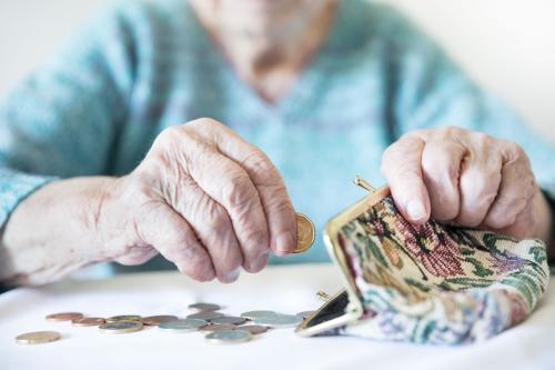 Older woman counting money from coin purse.