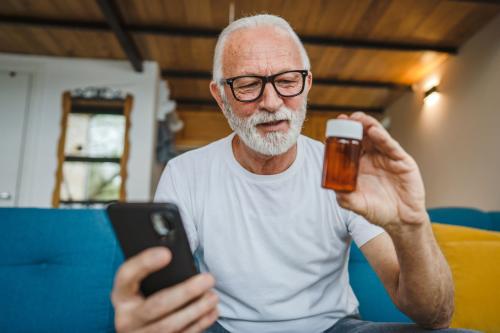 Older man with white hair looking at prescription bottle.