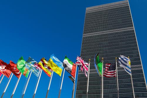 Photo taken in front of UN building in NY, with country flags flowing in the foreground.