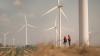 Young man and woman maintenance engineer team discussing on a wind turbine farm.