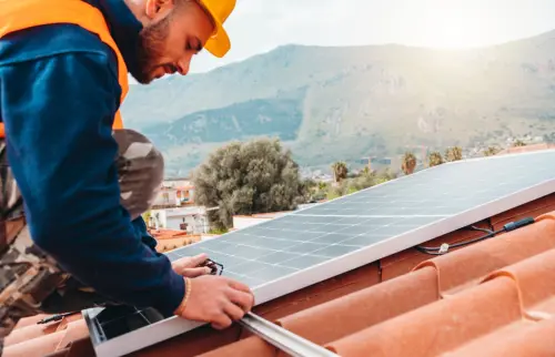 Construction worker installs solar panel on rooftop.