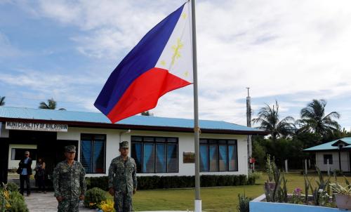 Filipino soldiers stand at attention near a Philippine flag at Thitu island in disputed South China Sea April 21, 2017.