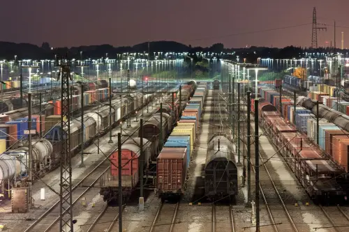 Freight trains sit stationary on tracks in a railyard at night