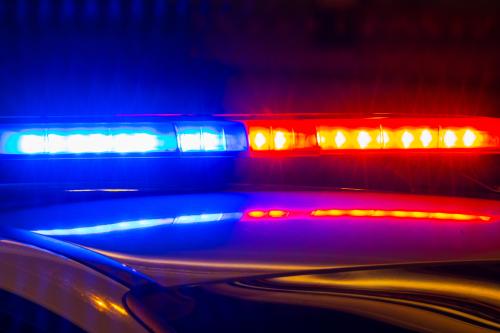 Detail of police car with lights flashing with red and blue colors on blurred background of city street