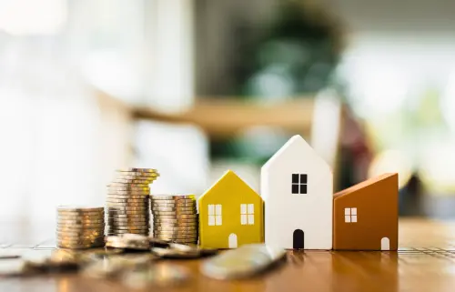 Stacks of coins next to houses represent the fall in mortgage rates