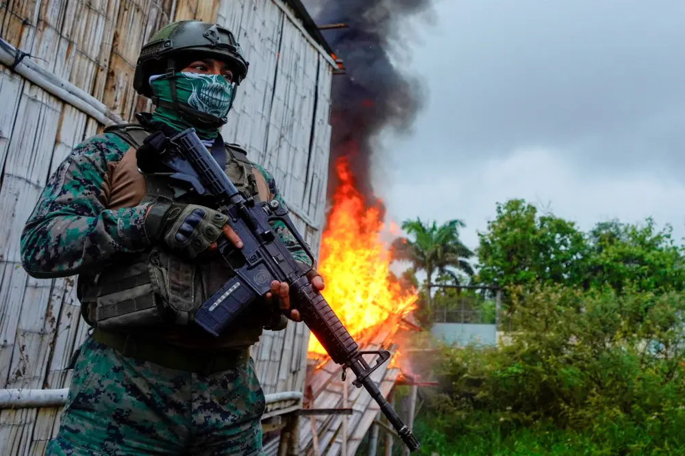 A soldier stands guard next to a house set on fire by police during a joint security operation in search for drugs and weapons in a low-income neighborhood on the outskirts of Guayaquil, in Duran, Ecuador, January 15, 2025.